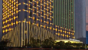 A modern hotel with a unique facade featuring illuminated patterns and a prominent green and white striped section. - Wanda Vista Nanning (Nanning)