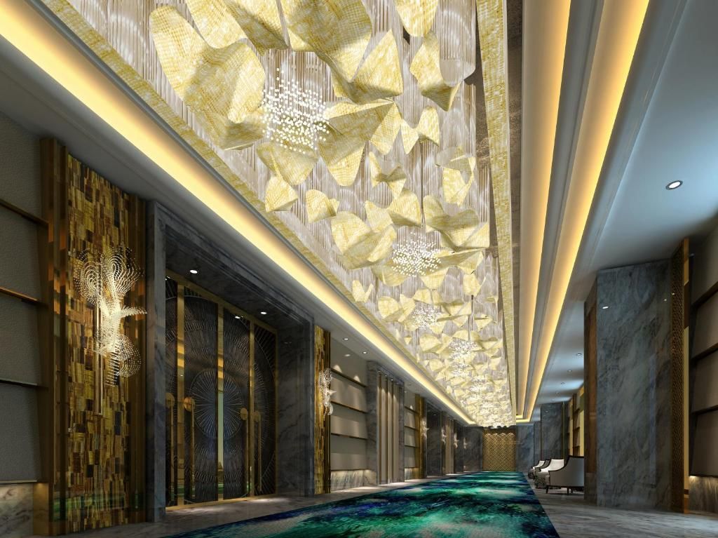A modern hotel lobby with a long corridor, decorative ceiling, and a patterned carpet.