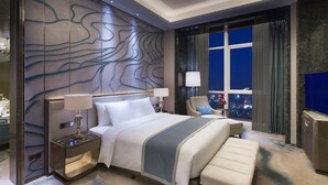 A modern hotel room with a large bed, a sitting area, a view of the city at night, and a decorative wall. - Wanda Vista Nanning (Nanning)