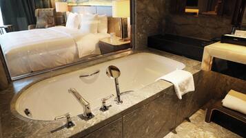 A modern bathroom with a large bathtub, a separate shower area, and a vanity with a mirror.