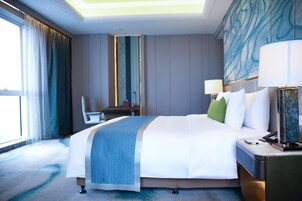 Una habitación de hotel con una cama grande, un escritorio, una silla y vistas al exterior.
