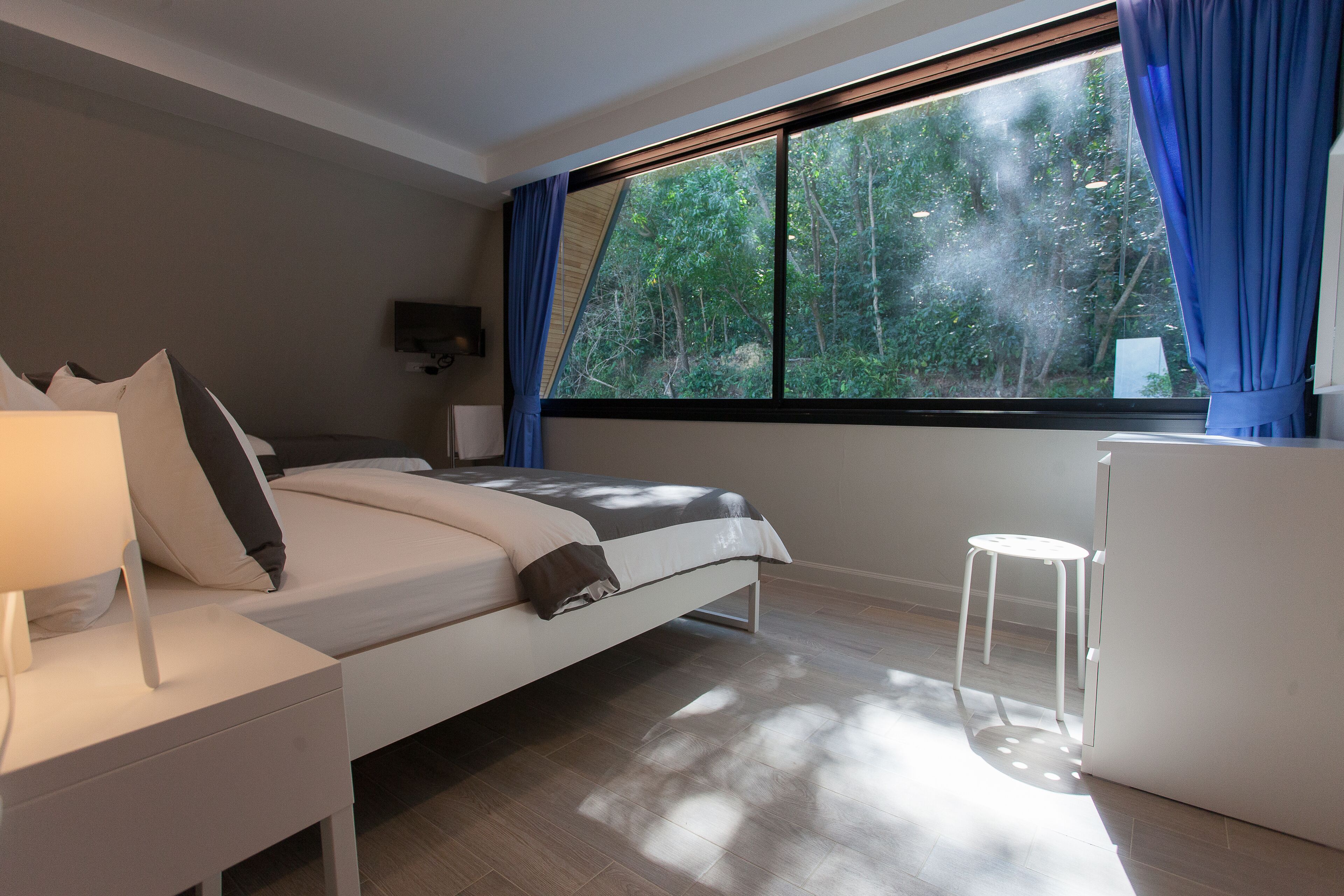 A modern bedroom with a bed, bedside table, and a small stool.