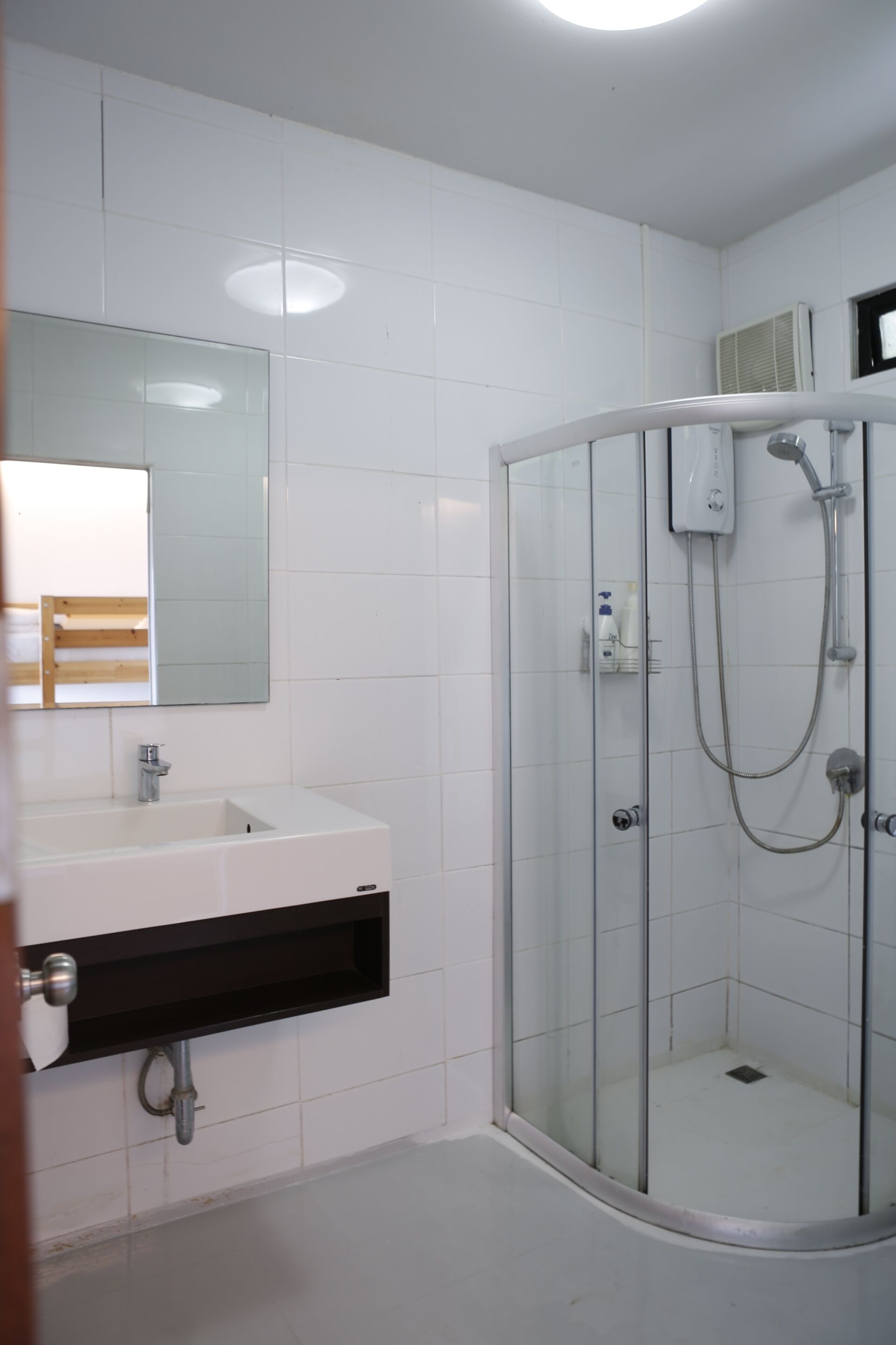 A modern bathroom with a glass-enclosed shower, a white sink with a black countertop, and a mirror above the sink.
