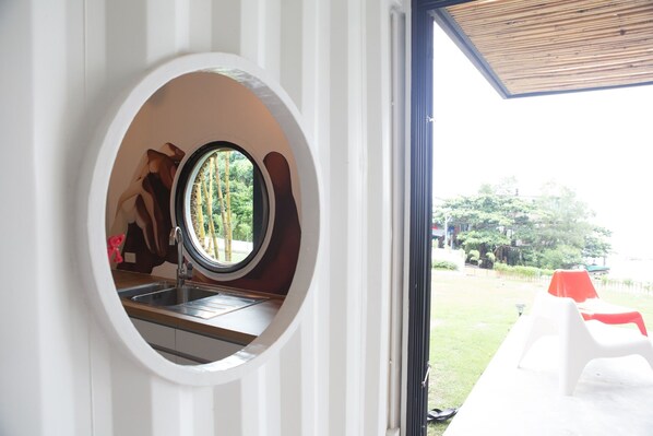 Una ventana circular que ofrece vistas a un jardín y muebles de exterior.
