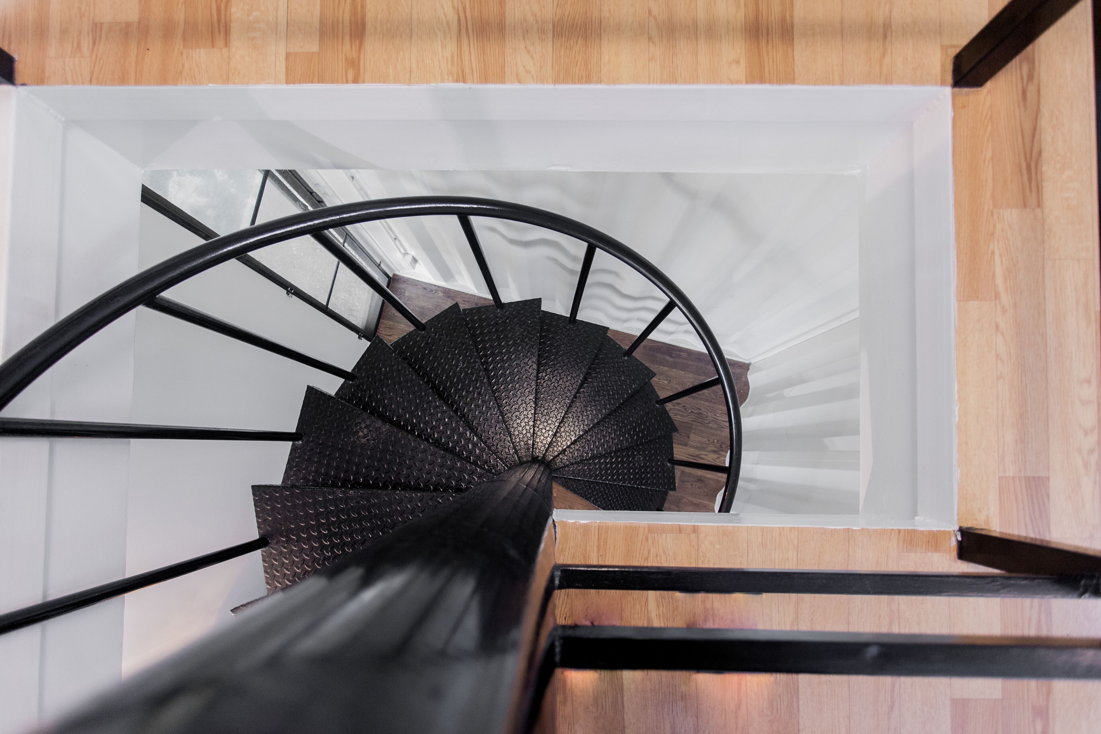 A spiral staircase with a black metal railing and wooden steps.