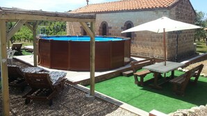 Un área de piscina con jacuzzi, terraza de madera y mobiliario exterior.