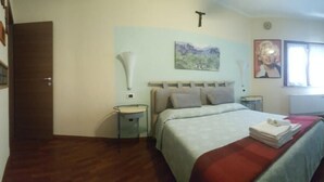 Un dormitorio con cama, mesitas de noche, televisor y armario.