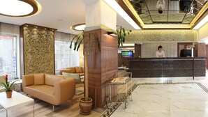 Eine moderne Hotelhalle mit Rezeption, Sitzgelegenheiten und einer Treppe.