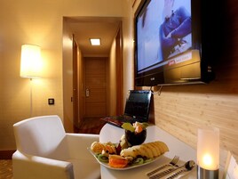 Una habitación de hotel con una cama, un escritorio con una computadora portátil, un televisor y una bandeja de frutas.