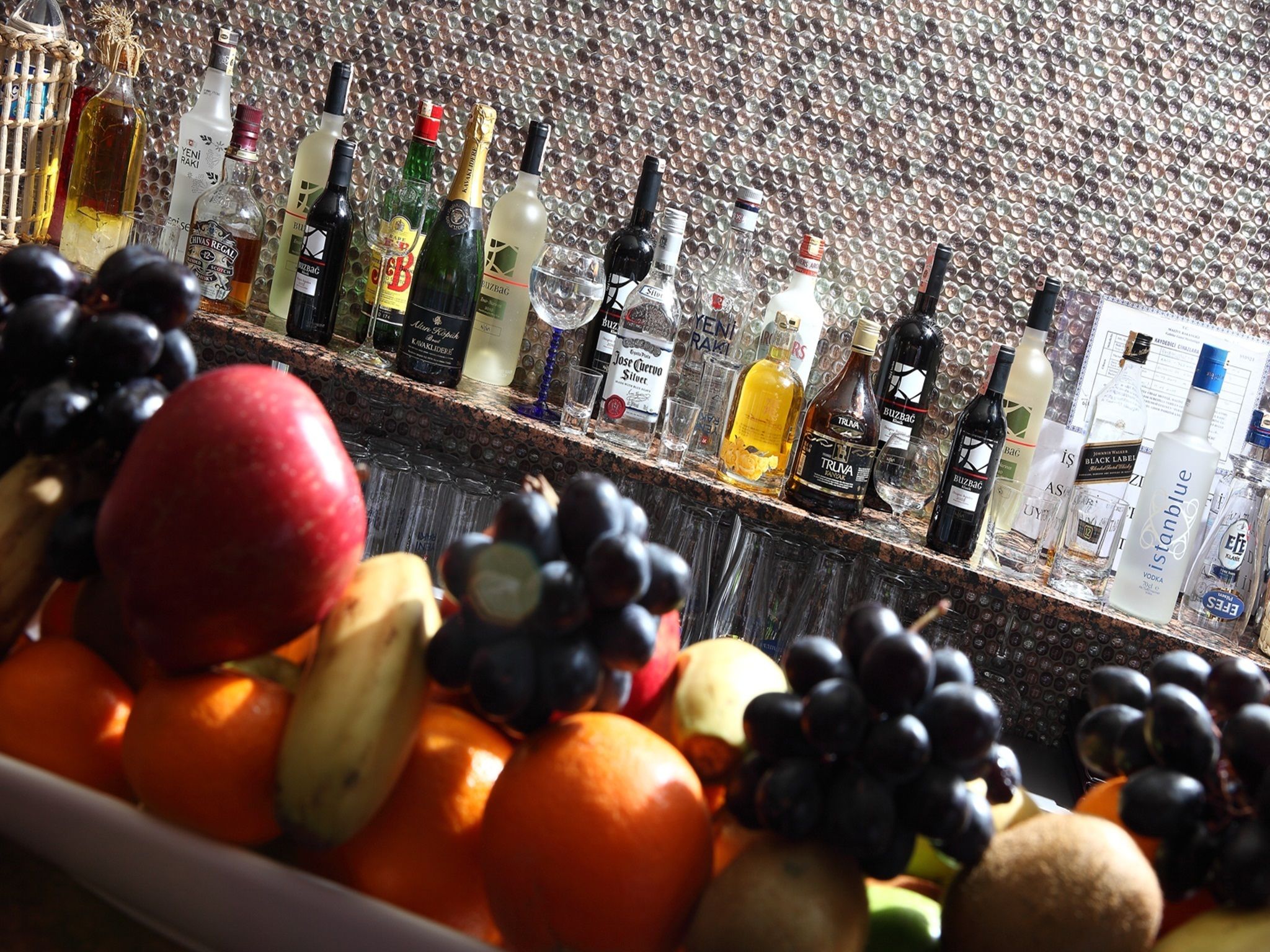 Una barra con diferentes botellas de licor y una variedad de frutas.