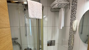 Ein modernes Badezimmer mit einer Duschkabine, einer Toilette und einem Waschbecken mit Spiegel.