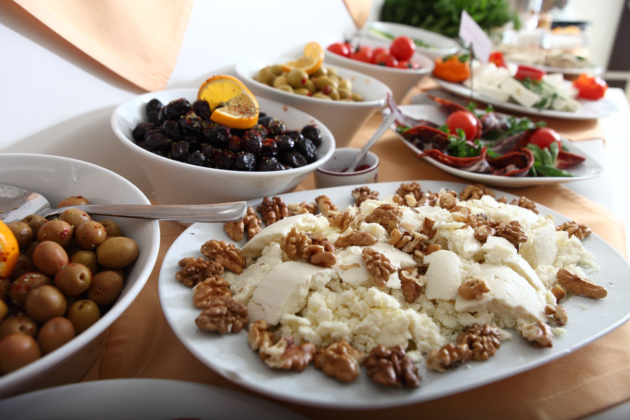 Diversos platos con aceitunas, nueces y una tabla de queso.