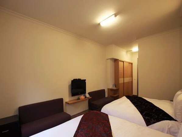 A hotel room with a bed, a sofa, a TV, and a wardrobe.