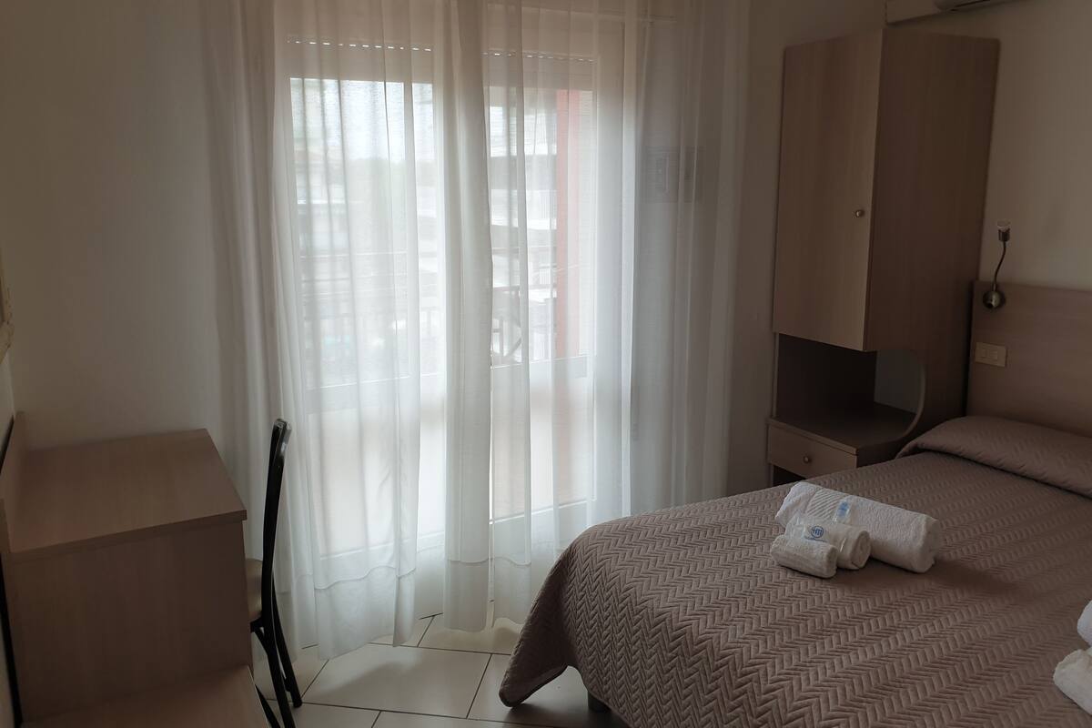 Une chambre d’hôtel avec un lit, une armoire, une chaise et un bureau.