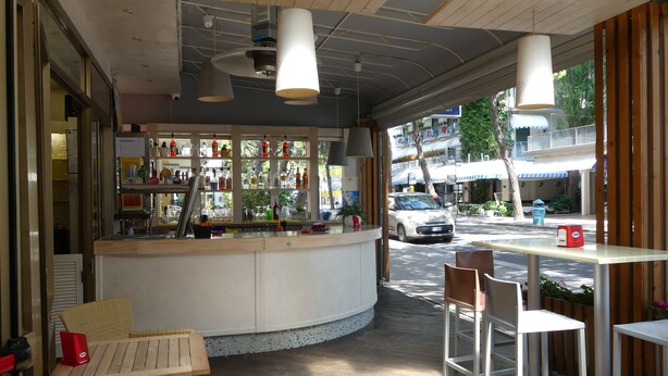 A cafe with a curved counter, wicker furniture, and hanging pendant lights. - Hotel Madison (Jesolo)