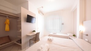 A modern hotel room with a bed, a desk, a TV, and a window with sheer curtains. - Hotel Madison (Jesolo)
