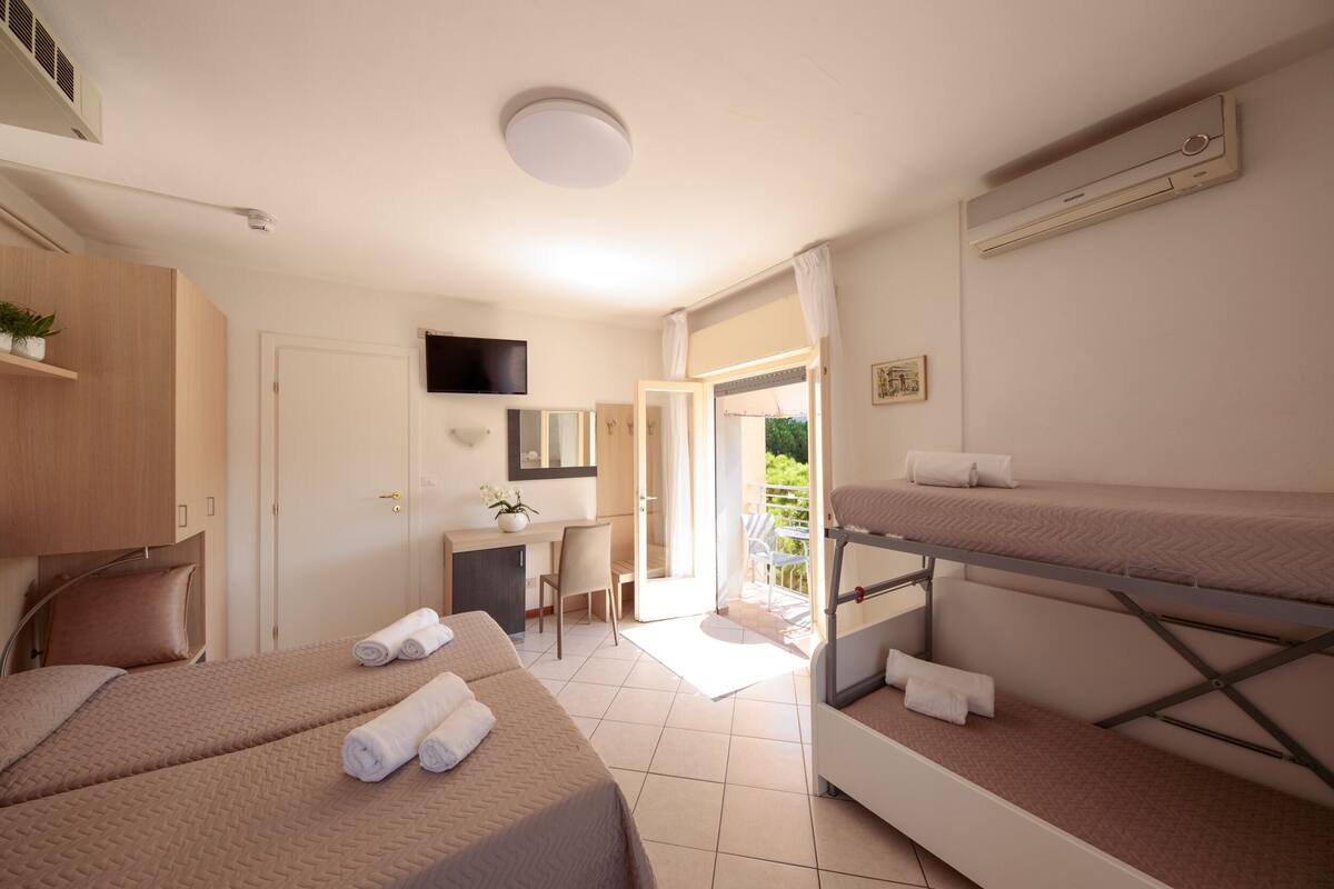 Une chambre d’hôtel avec deux lits, un bureau, une chaise, un téléviseur et un appareil de climatisation.