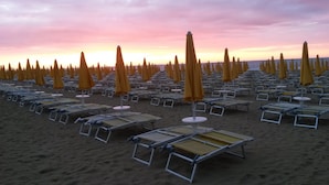 A beach with rows of sun loungers and yellow umbrellas. - Hotel Madison (Jesolo)