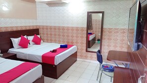 A hotel room with two beds, a wooden headboard, a mirror, a small desk, and a chair. - Hotel Bharat Palace (Jaipur)