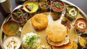 A traditional Indian meal served on a metal plate with various dishes including rice, flatbreads, and multiple curries. - Hotel Bharat Palace (Jaipur)