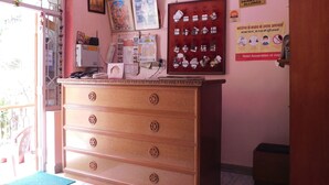 A hotel room with a wooden dresser, a desk with a computer, a window with a view, and a door. - Hotel Bharat Palace (Jaipur)