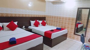 A hotel room with three beds, each with white bedding and red pillows. There is a wooden headboard, a mirror, and a tiled floor. - Hotel Bharat Palace (Jaipur)