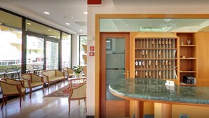 Ein Hotel-Empfangsbereich mit einer Marmor-Theke, Holzregalen mit Auszeichnungen und einer Sitzecke mit Stühlen und einem Tisch.