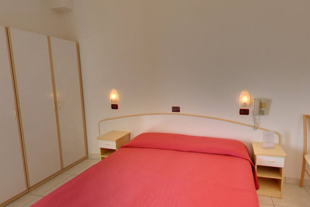 Ein Schlafzimmer mit Bett, Nachttischen, einem Sessel und einem Kleiderschrank.