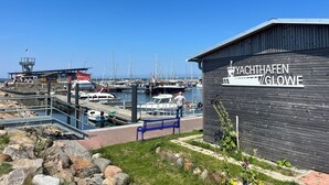 A marina with boats docked, a wooden building labeled "YACHTHAFFEN GLOWE", and a small dock area with a bench. - Gasthaus & Pension Zur Schaabe (Glowe)