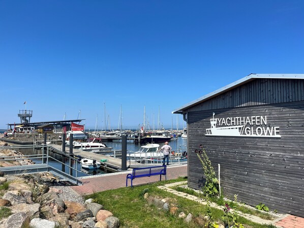 A marina with boats docked, a wooden building labeled "YACHTHAFFEN GLOWE", and a small dock area with a bench. - Gasthaus & Pension Zur Schaabe (Glowe)