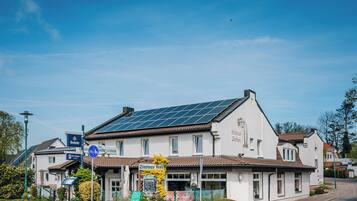 A white building with solar panels on the roof, a sign for 'Zimmer frei', and a 'Herforder' sign.
