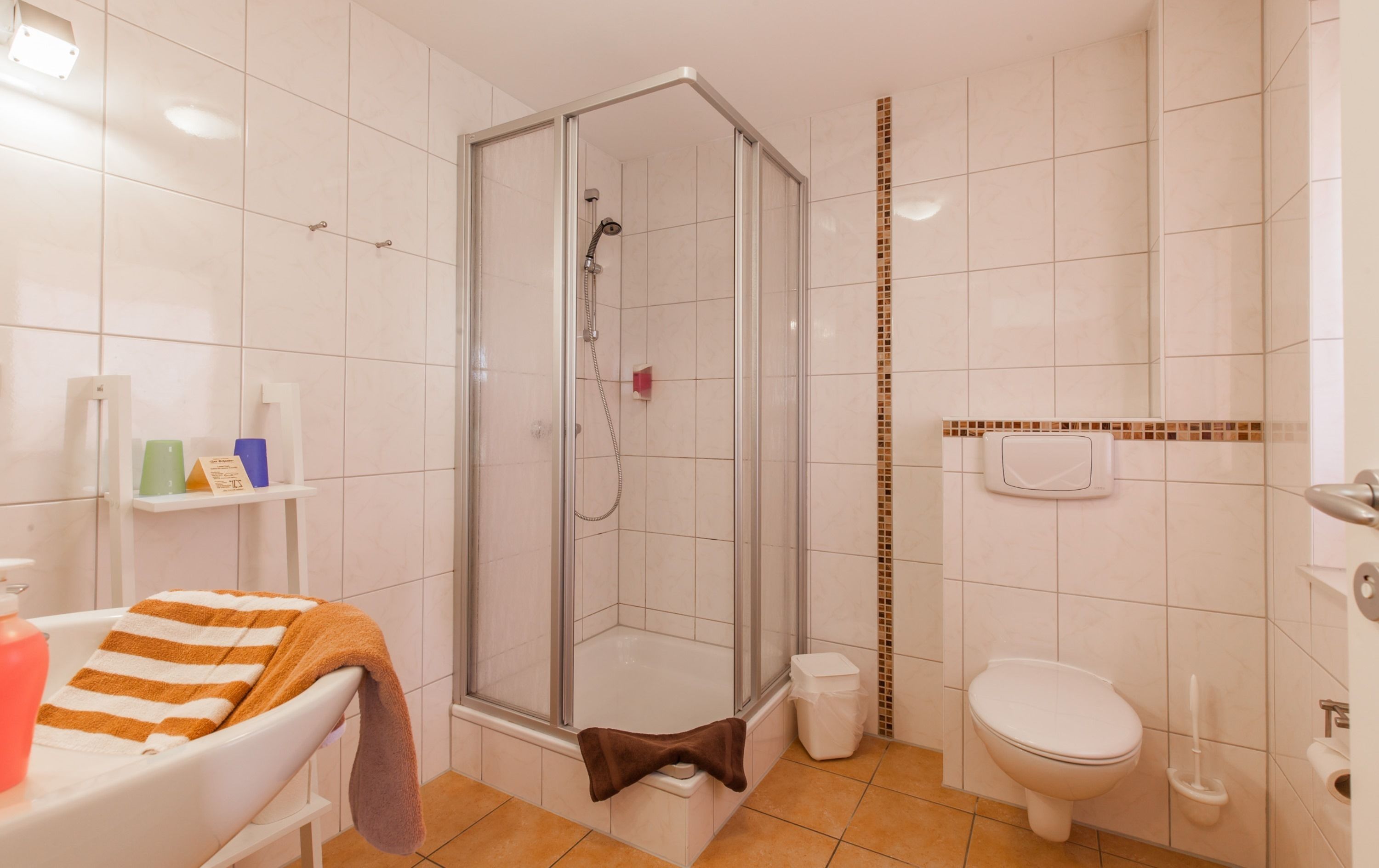 A bathroom with a glass-enclosed shower, a white toilet, and a sink with a towel.