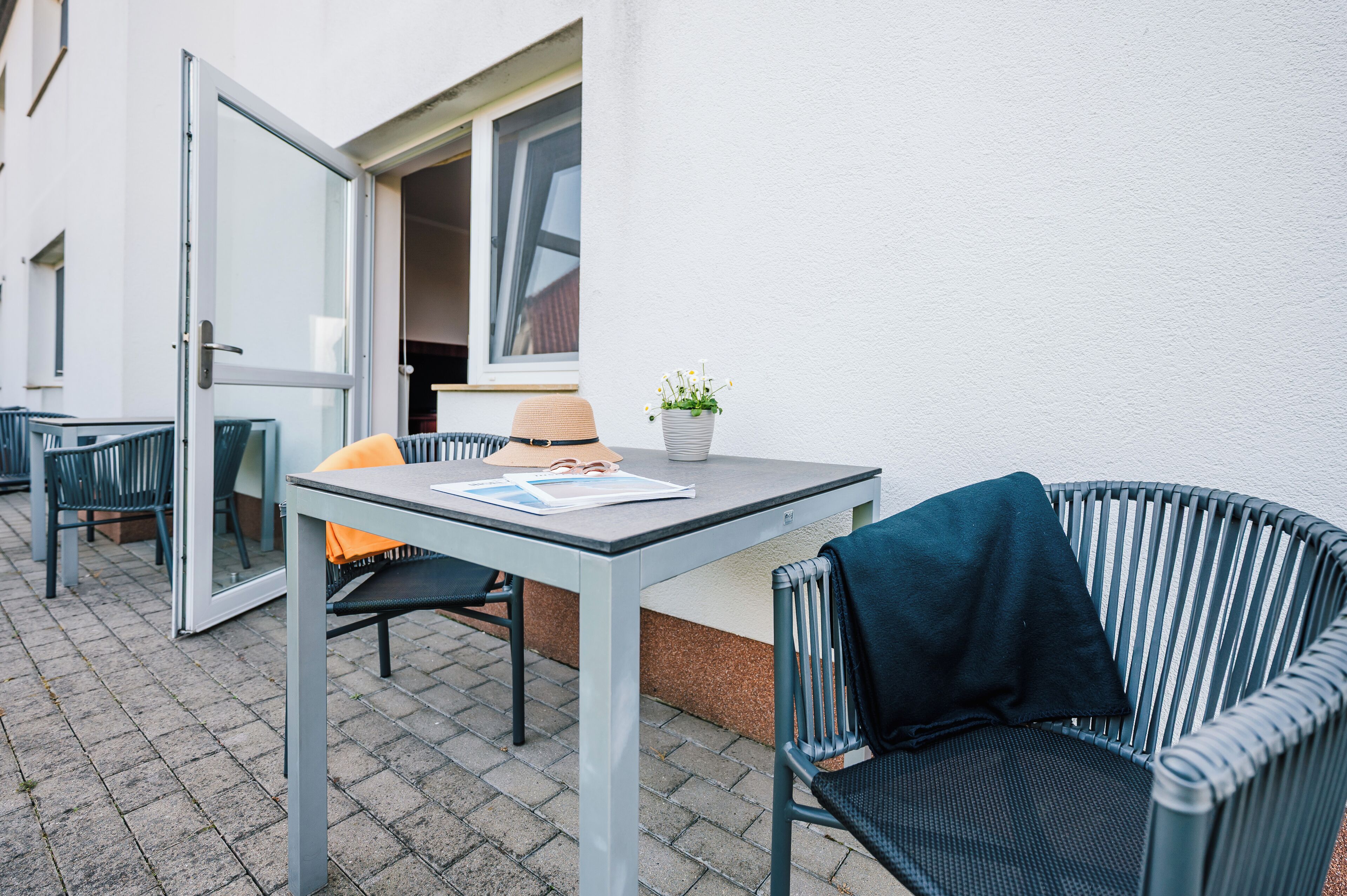 Un espace extérieur aménagé avec une table, des chaises et un pot de fleurs.
