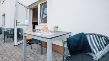 Un espace extérieur aménagé avec une table, des chaises et un pot de fleurs.