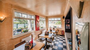 A restaurant with checkered flooring, multiple tables and chairs, and large windows with views of the outside. - Gasthaus & Pension Zur Schaabe (Glowe)