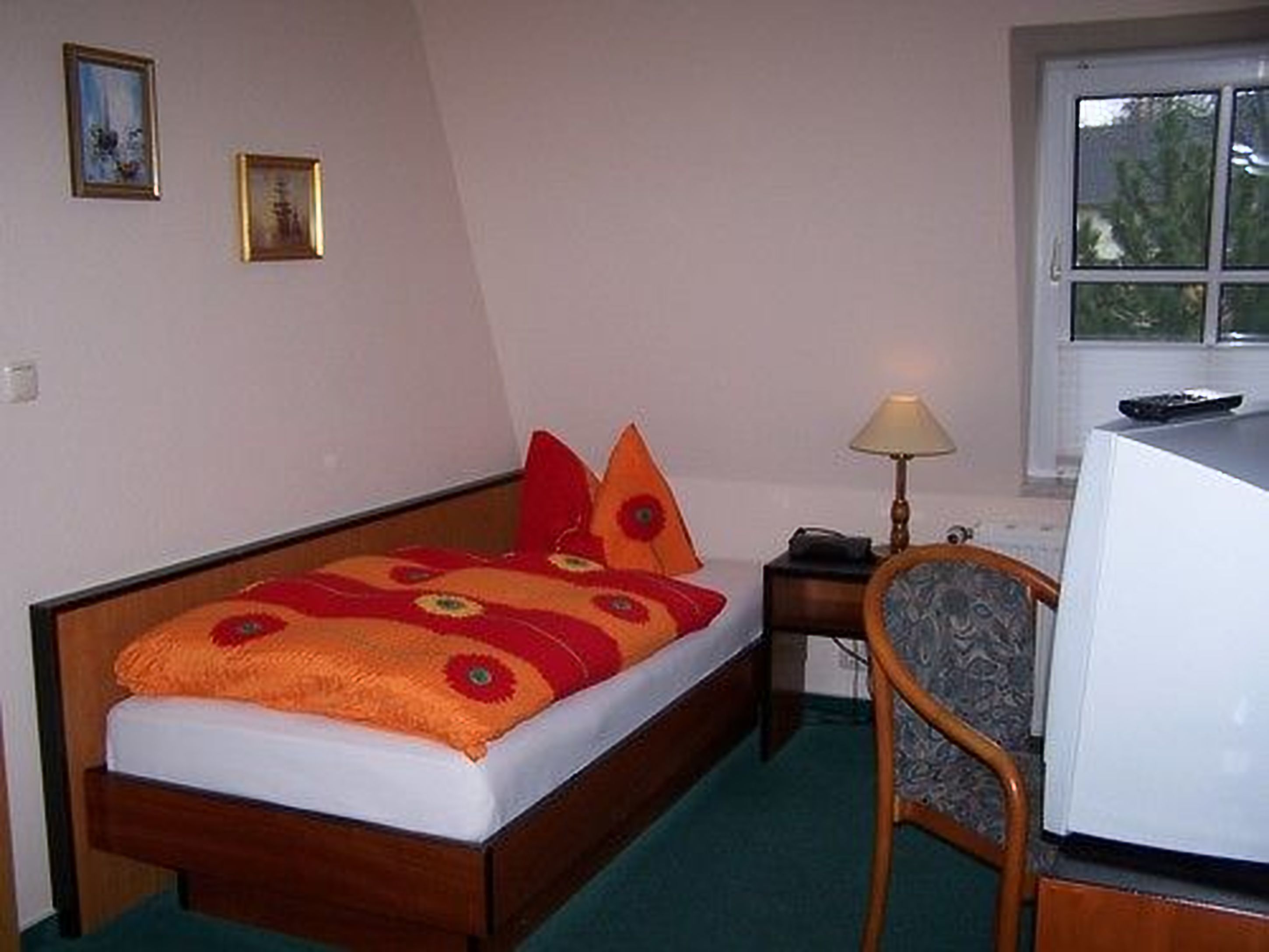 Une chambre à coucher avec un lit, un bureau, une chaise et une fenêtre.