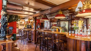 A bar with wooden furniture, a statue, and various bottles and glasses. - Gasthaus & Pension Zur Schaabe (Glowe)