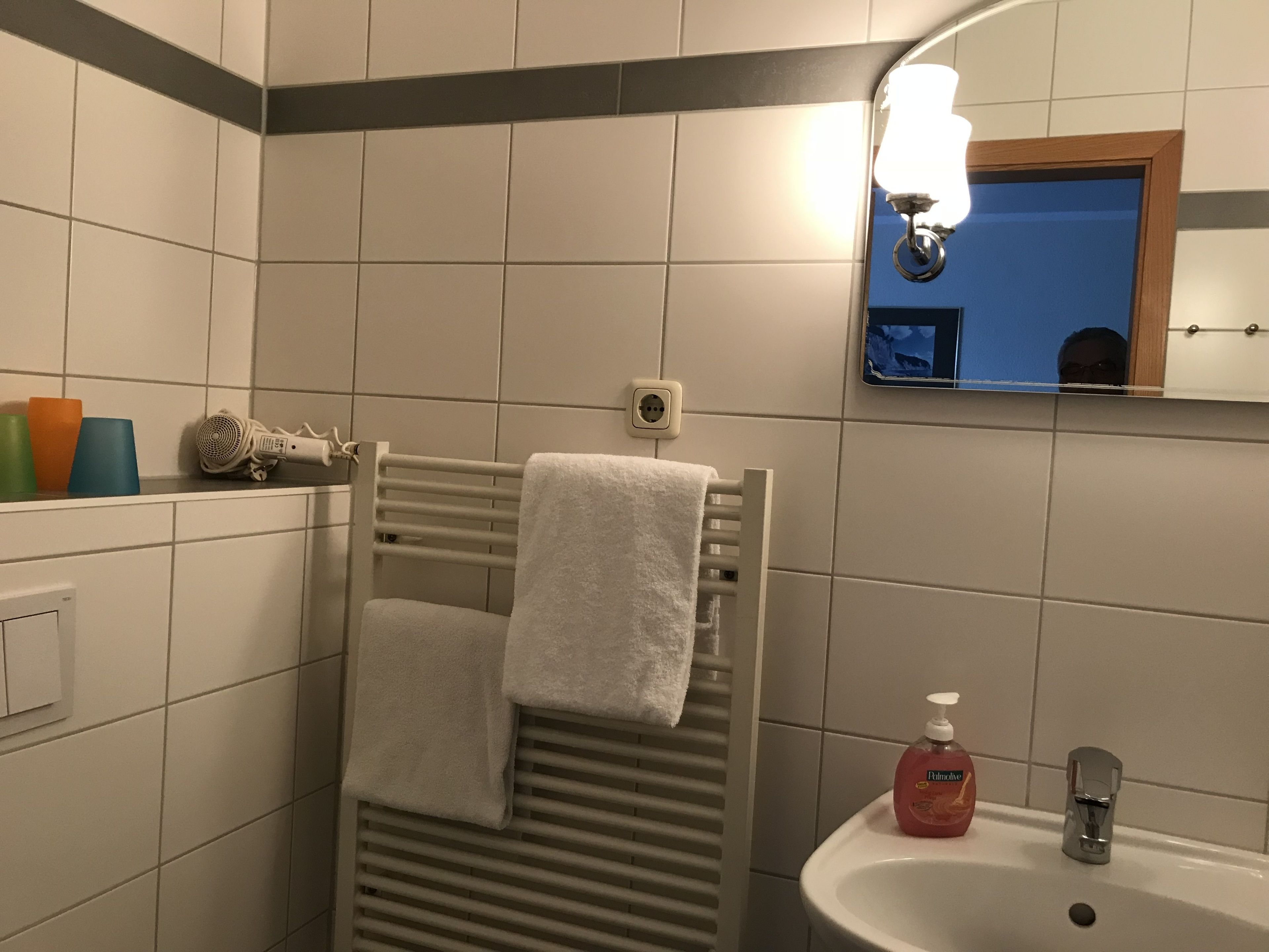 Une salle de bain équipée d’un porte-serviettes, d’un lavabo, d’un miroir et d’un savon.