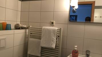 Une salle de bain équipée d’un porte-serviettes, d’un lavabo, d’un miroir et d’un savon.