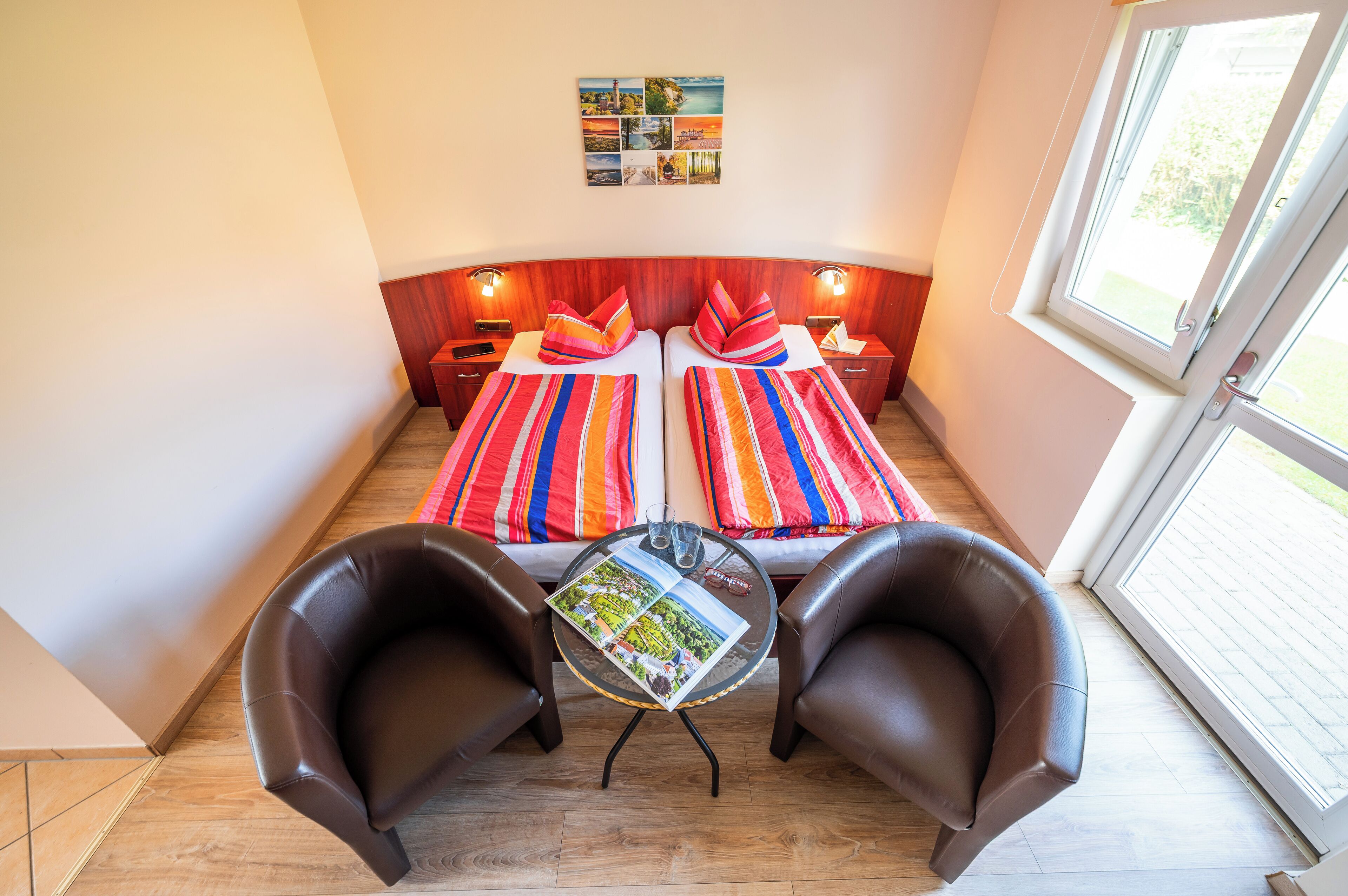 A room with two beds, a small table with a magazine, and two leather chairs.