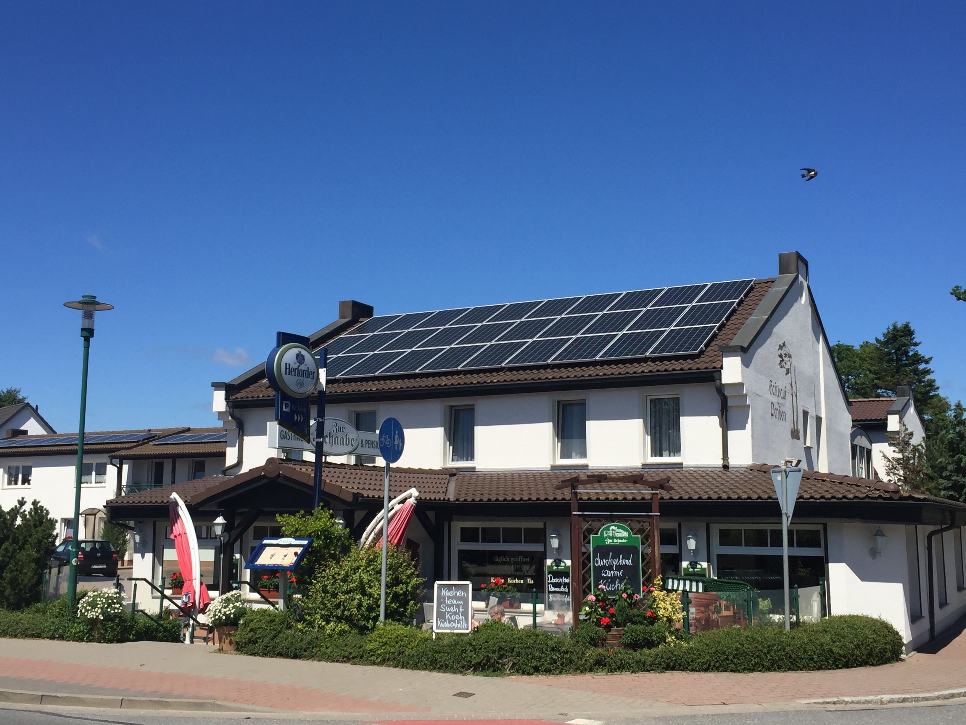 Ein Gebäude mit Solaranlage auf dem Dach, einem Restaurantschild und einem Schild für eine Küche.