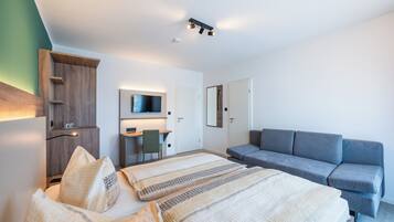 Una habitación de hotel moderna con una cama, un sofá, un escritorio y un televisor.