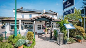 A hotel entrance with a covered patio, a sign for 'Herforder', and a parking sign. - Gasthaus & Pension Zur Schaabe (Glowe)
