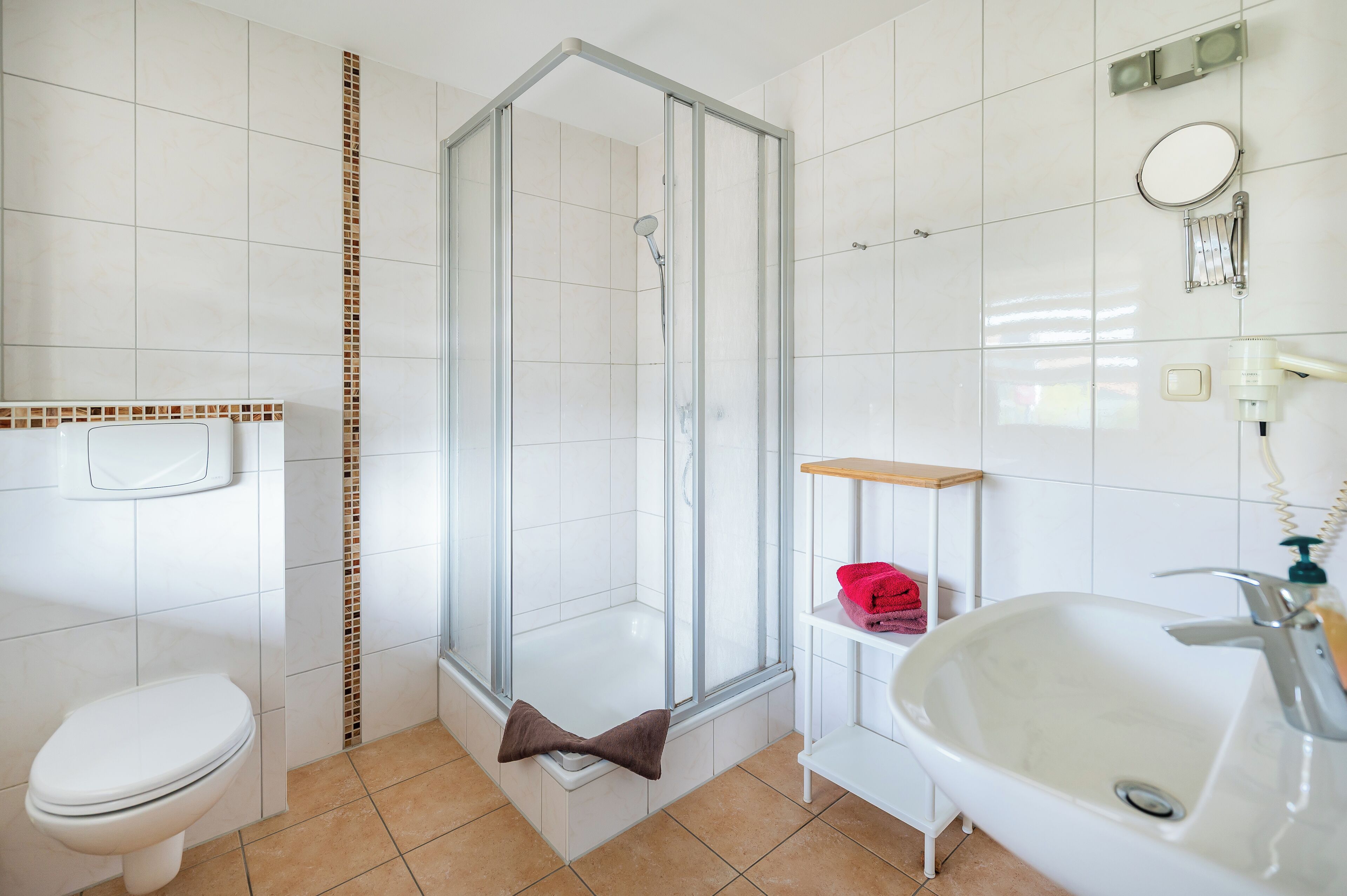 Une salle de bain avec une douche à parois de verre, un lavabo blanc et des toilettes.