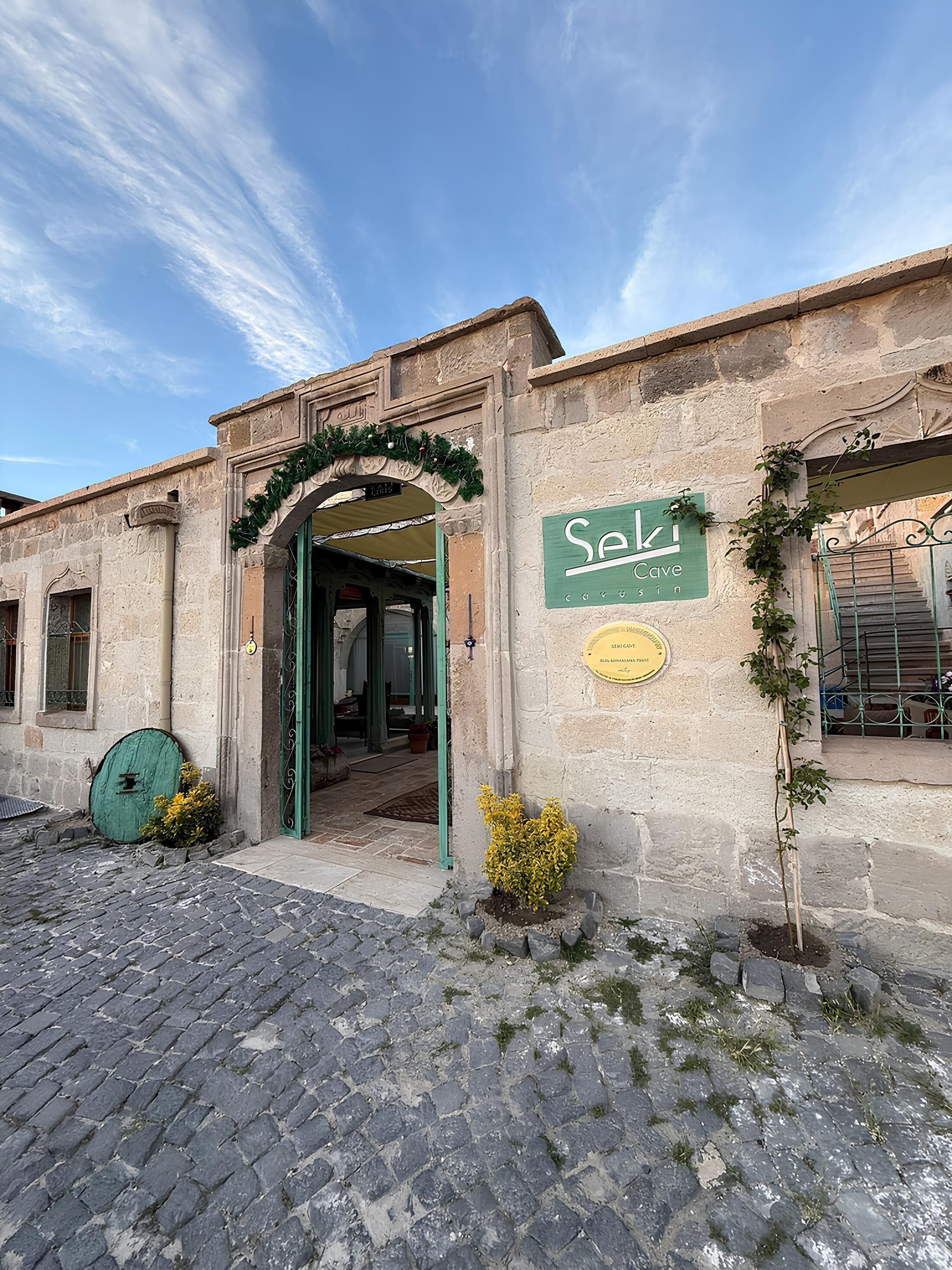 Un edificio de piedra con una puerta verde y un letrero que dice 'Seki Cafe'.
