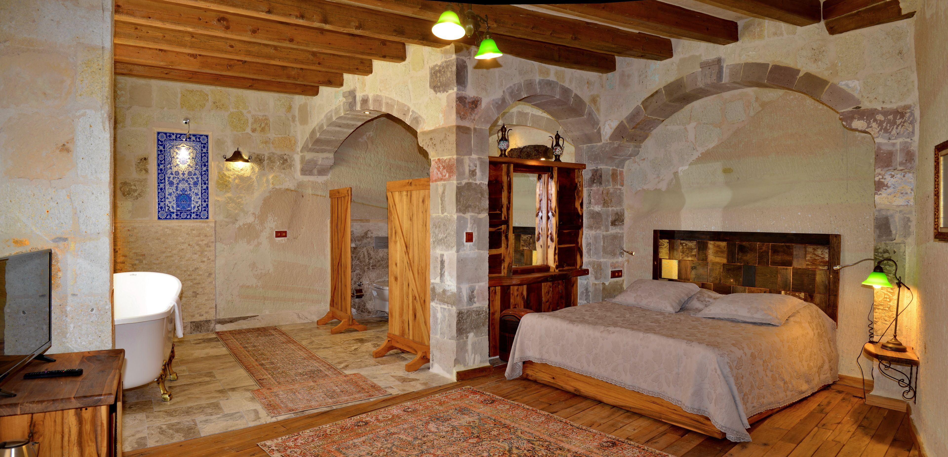 A rustic bedroom with a wooden bed, a stone wall, and a traditional bath.