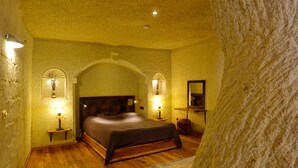 Quarto com piso de madeira, uma cama grande, duas luminárias de cabeceira e um espelho na parede.