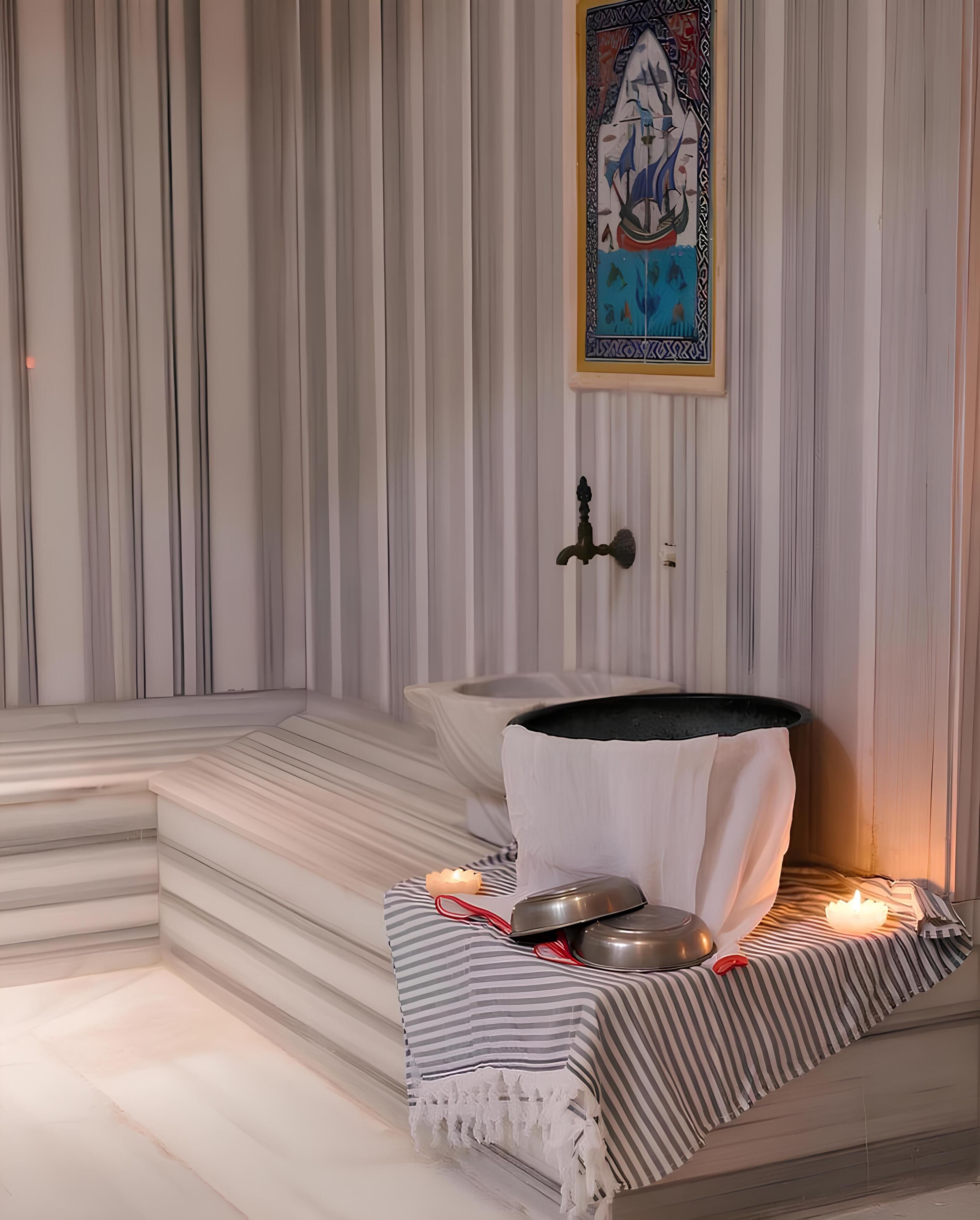 A spa room with a stone bench, a heated stone bath, and a decorative wall with a framed artwork.