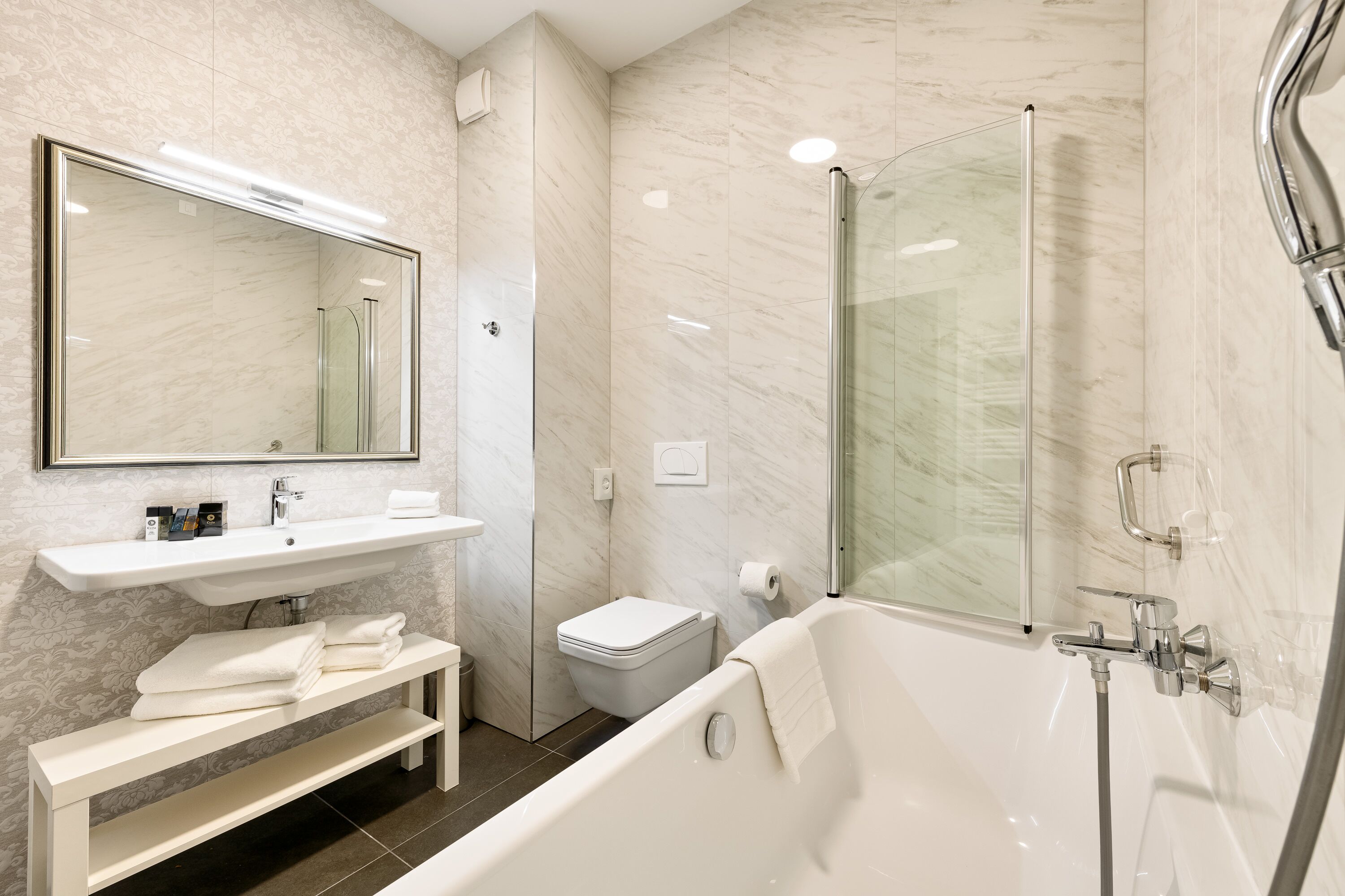 A modern bathroom with a glass-enclosed shower, a white sink, and a bathtub.