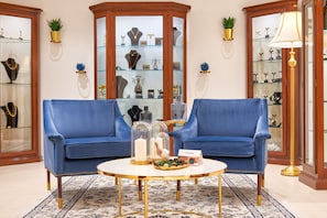 A room with two blue sofas, a round coffee table, and a glass display cabinet with jewelry. - Hotel Cvita (Split)